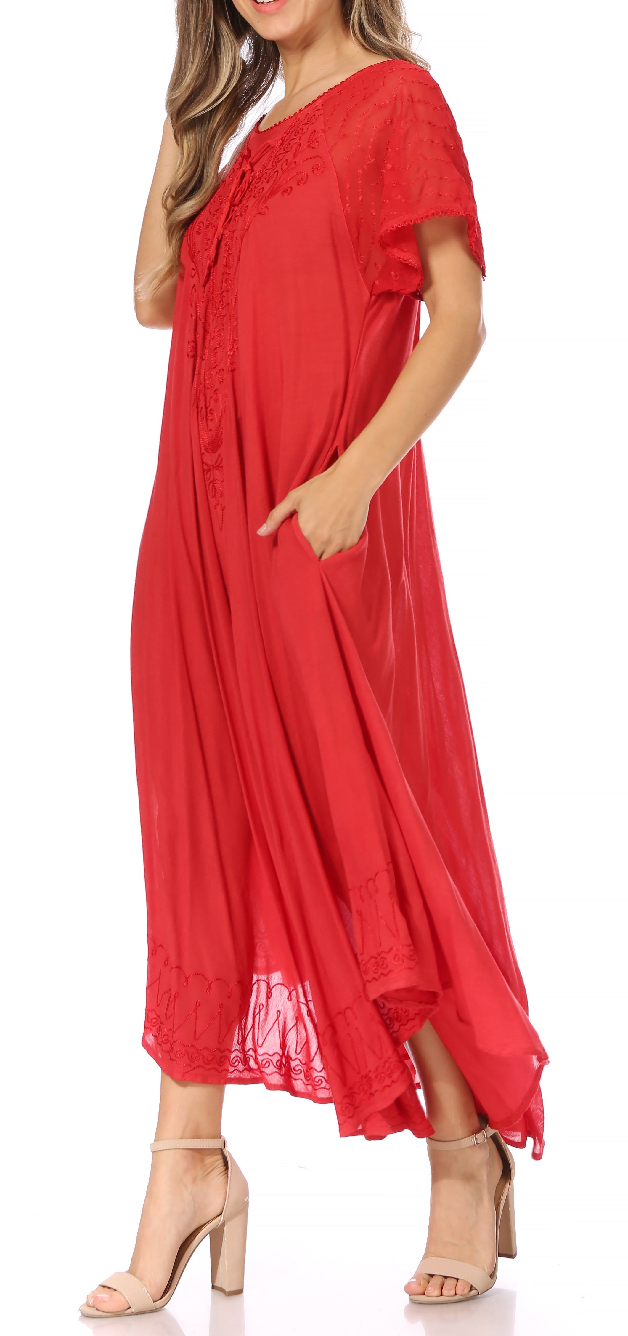Woman wearing a long, flowing red-colored dress with lace sleeves on a white background