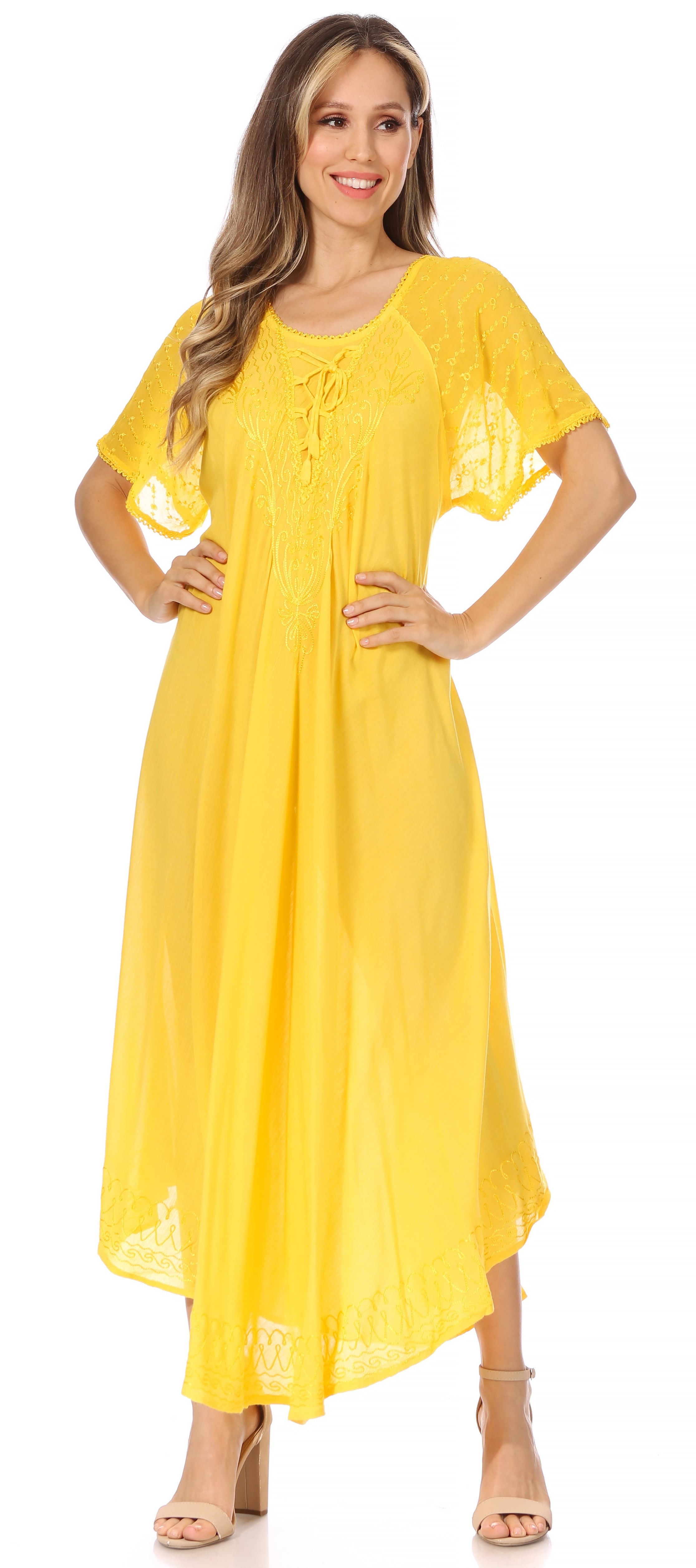 Woman wearing a long, flowing yellow-colored dress with lace sleeves on a white background