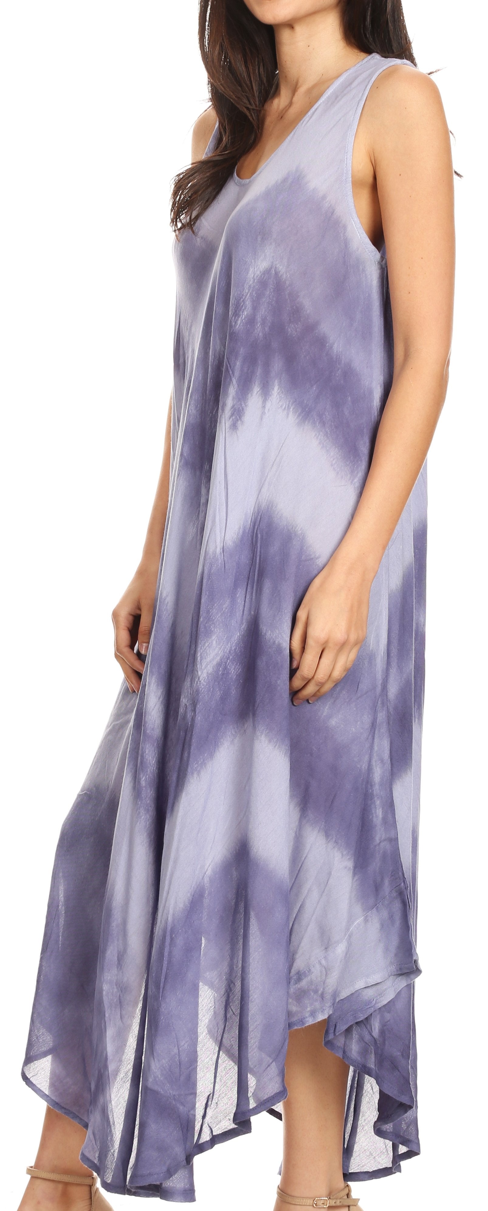 Woman wearing a sleeveless, tie-dye dress with a high-low hem on a plain background
