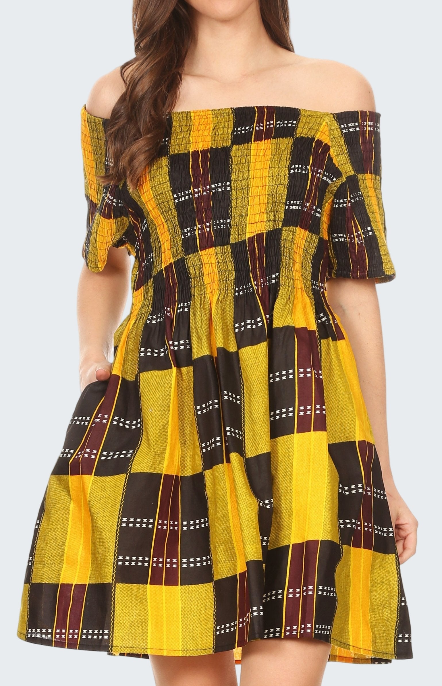 Woman wearing a yellow and black checkered dress with off-shoulder sleeves.