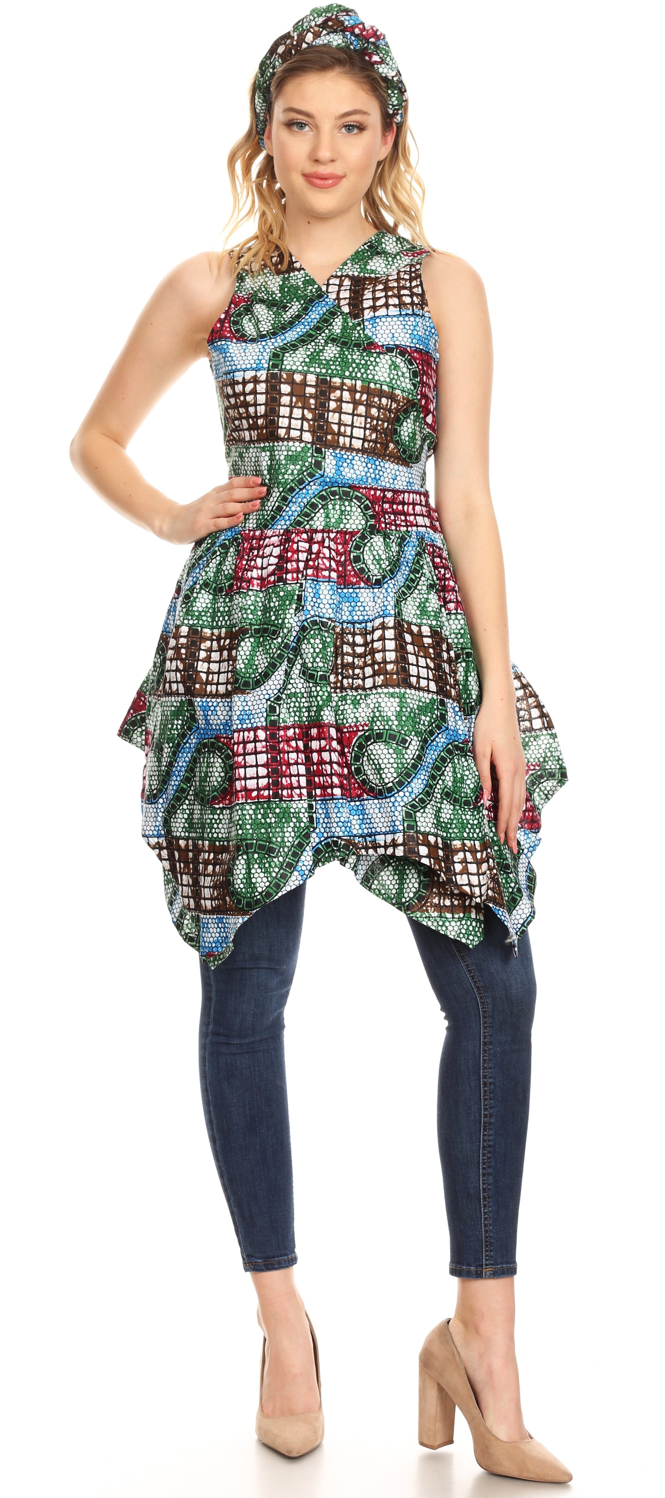 Woman wearing a colorful patterned dress with a hood and dark jeans on a white background