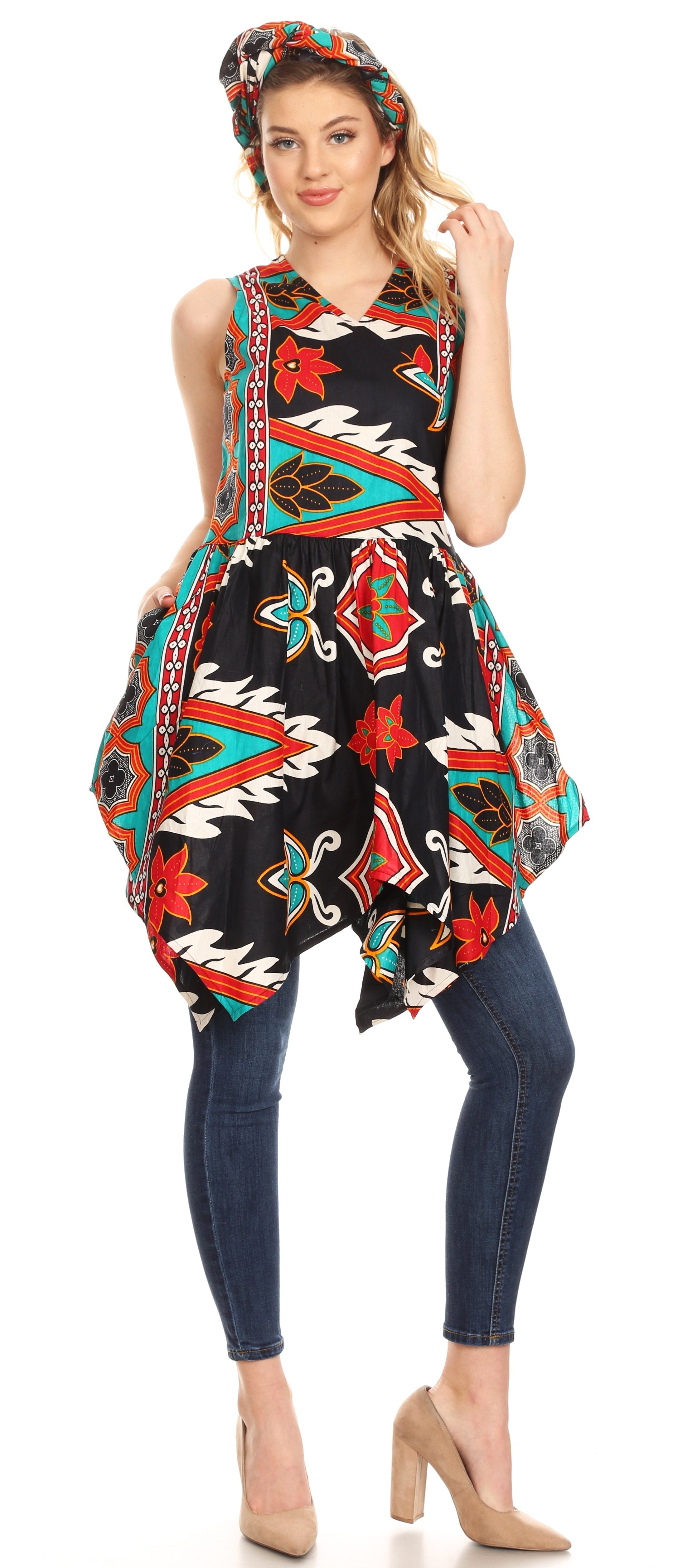 Woman wearing a colorful patterned dress over jeans on a white background