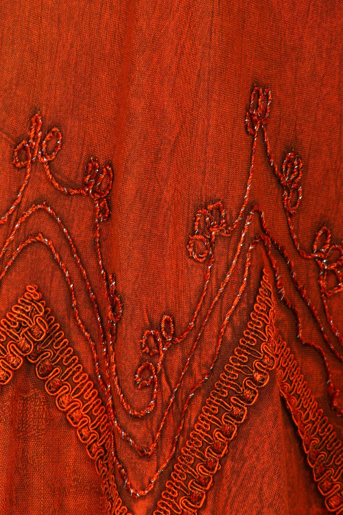 Close-up of embroidered fabric with intricate patterns on a red background