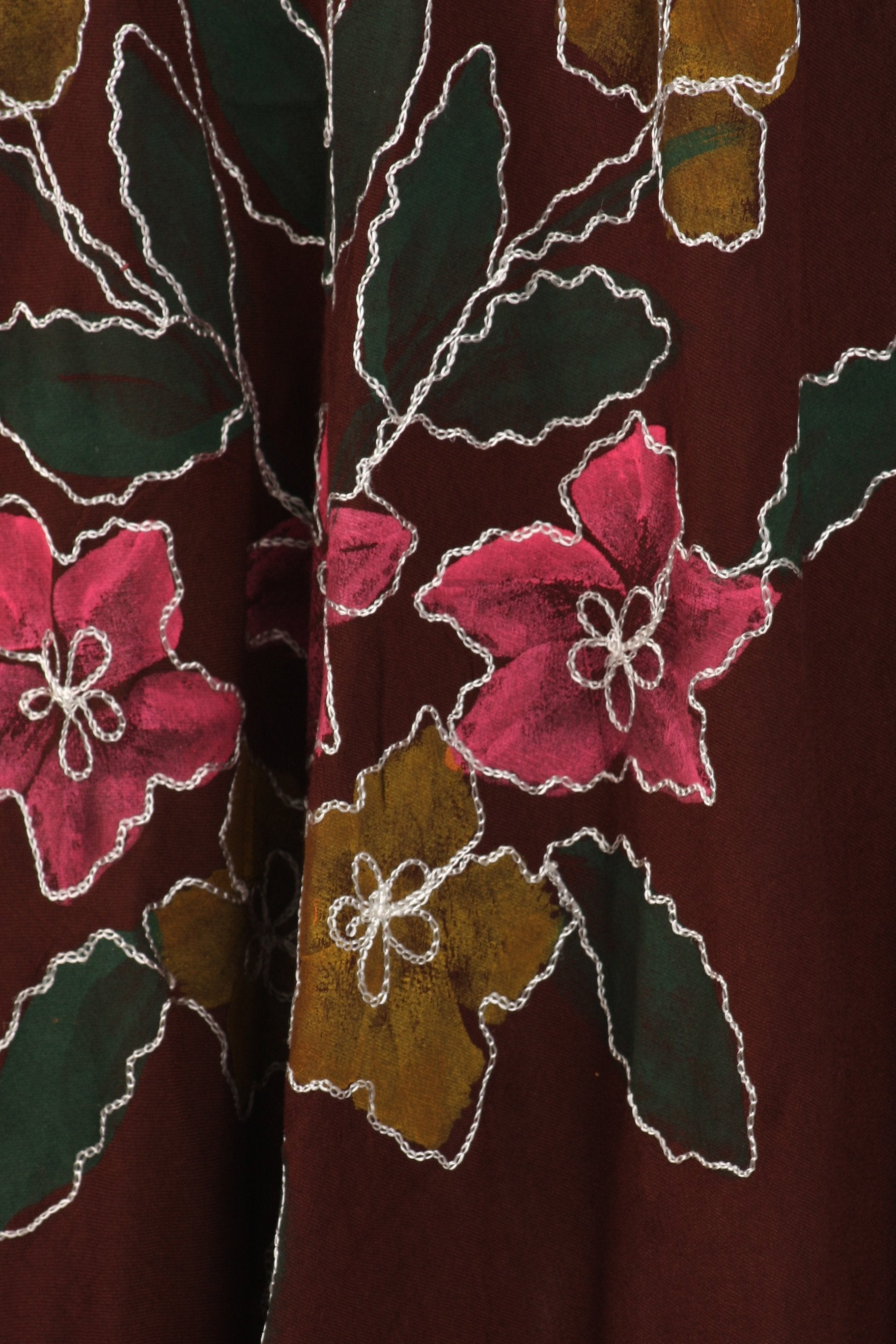 Close-up of a floral patterned fabric with pink flowers and green leaves on a brown background.