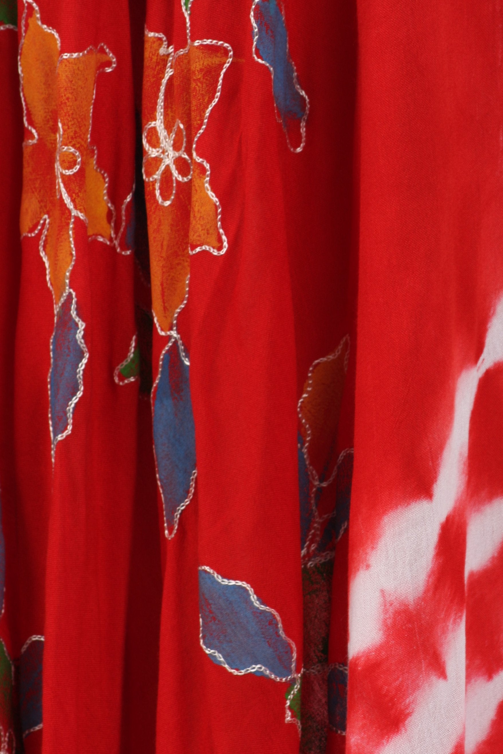 Close-up of a red fabric with floral patterns in orange, blue, and white.