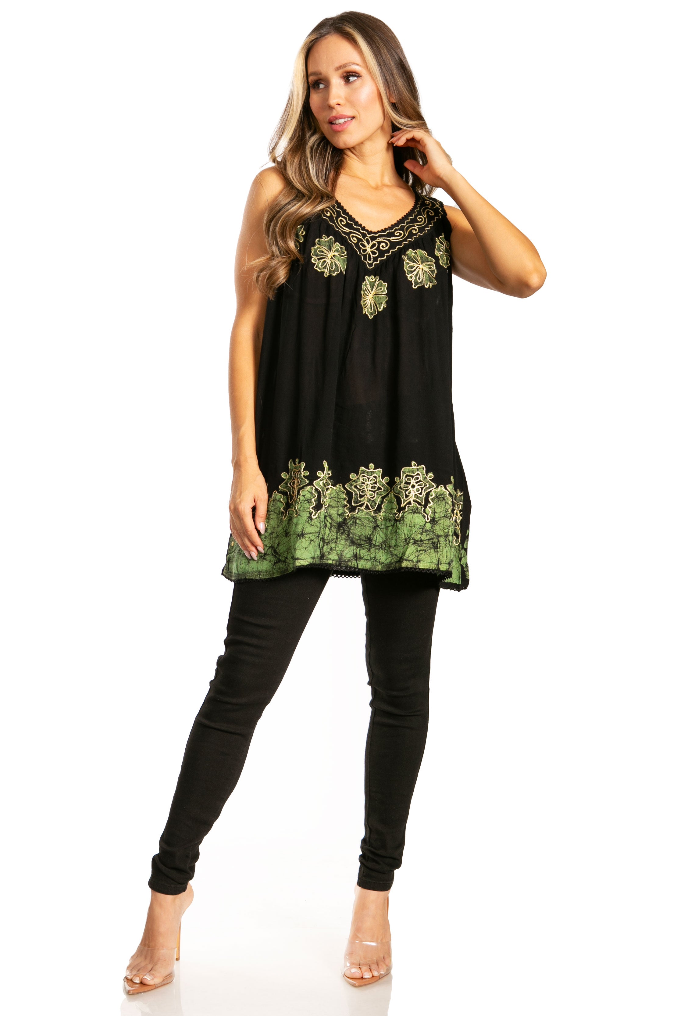 Woman wearing a black sleeveless top with green embroidery and black pants on a white background