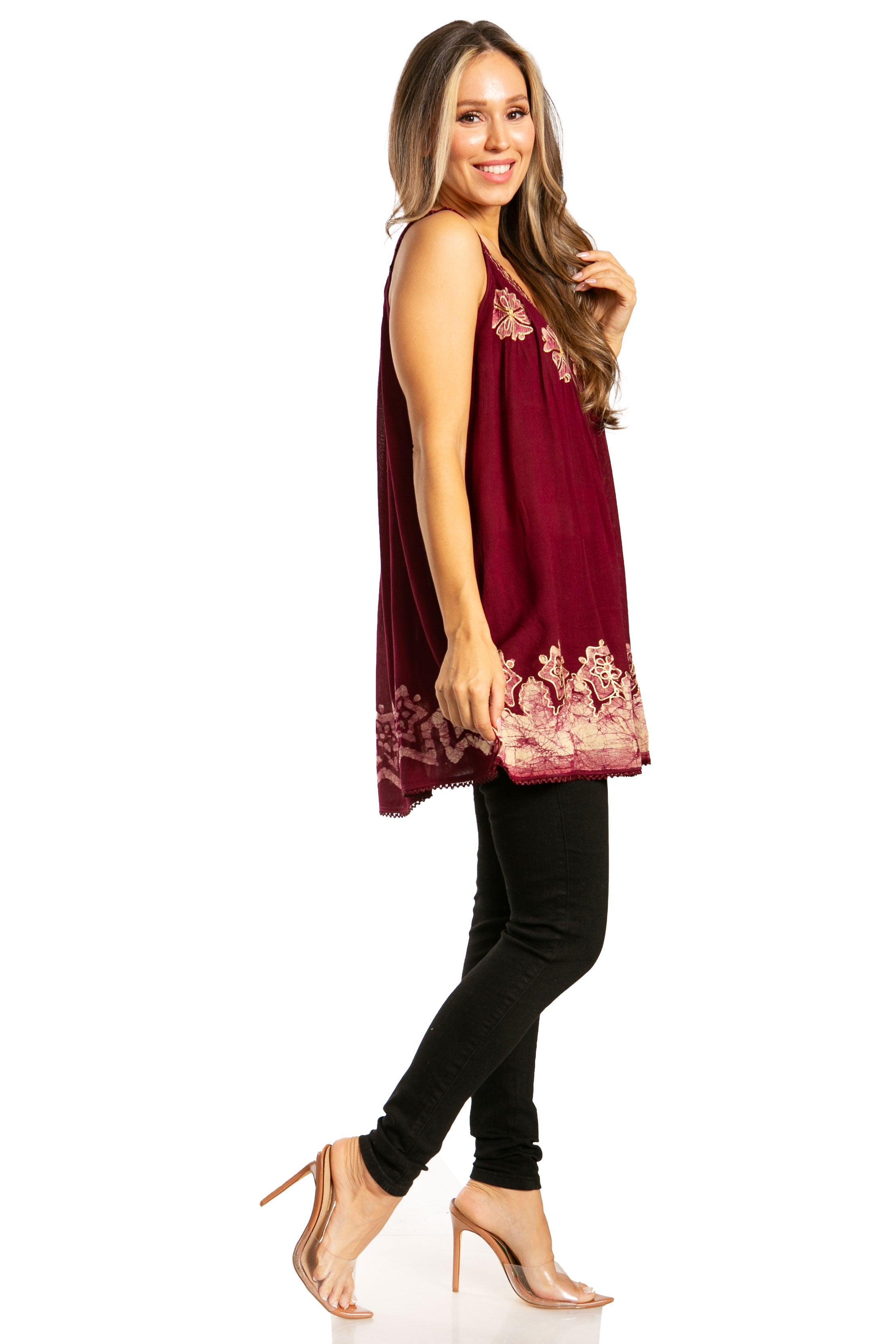 Woman wearing a burgundy top with floral embroidery and black pants on a white background