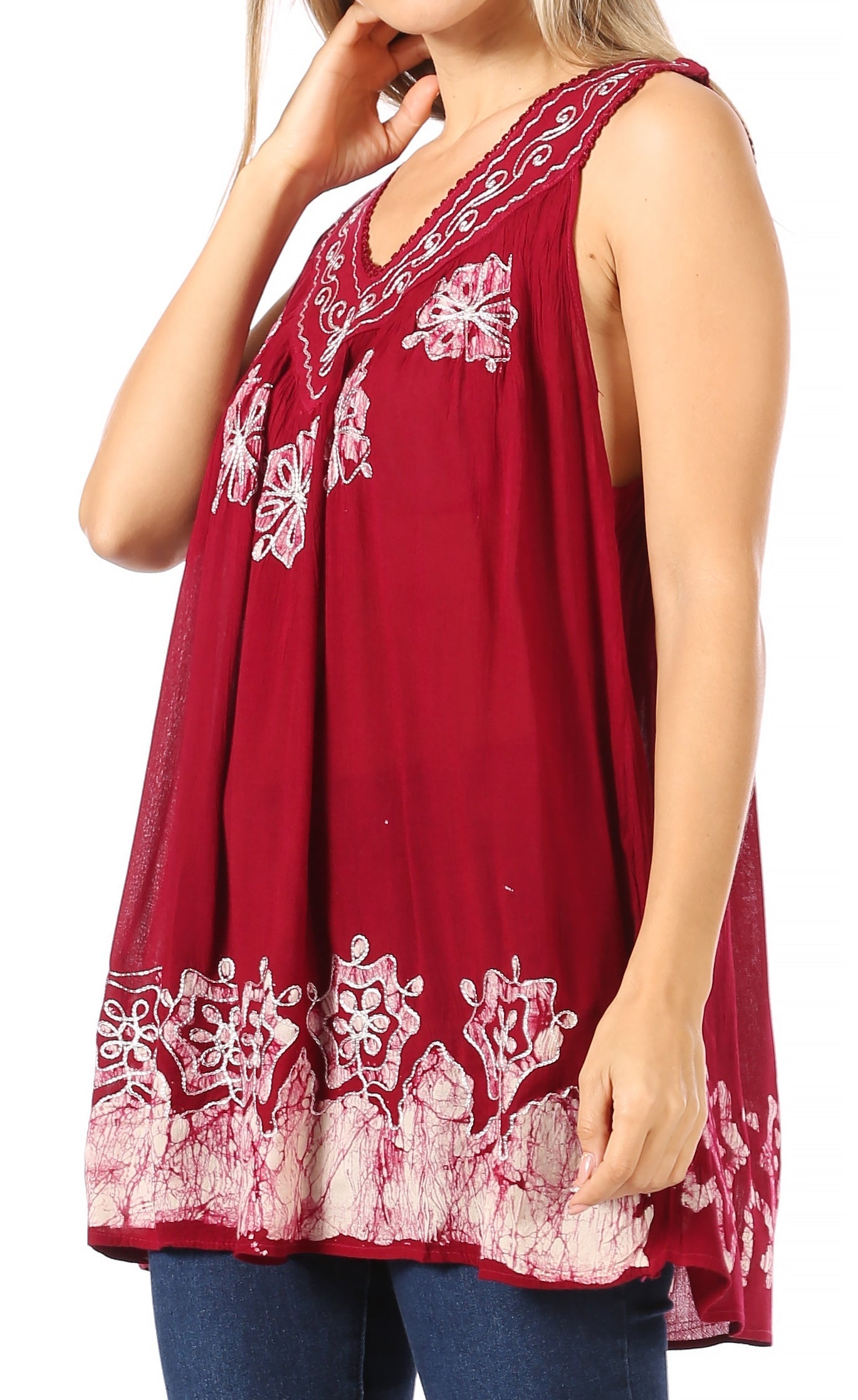 Red sleeveless top with white floral embroidery worn by a person on a white background