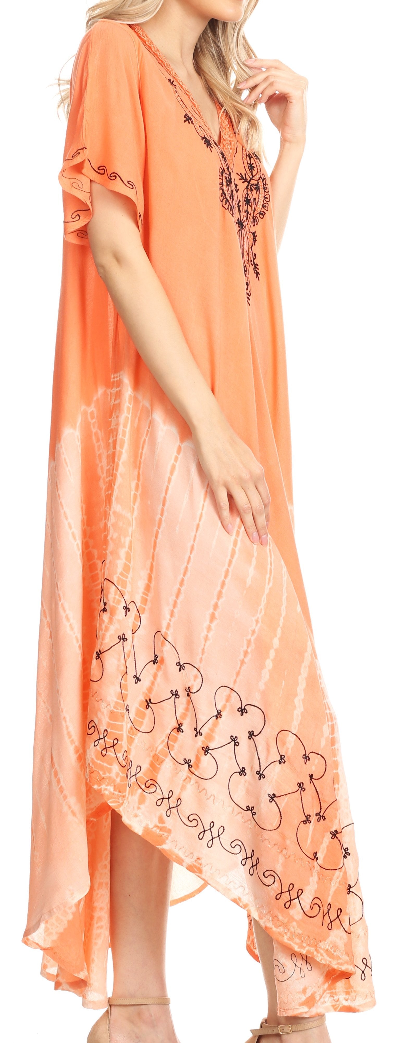 Woman wearing a long, light orange dress with floral embroidery on a white background