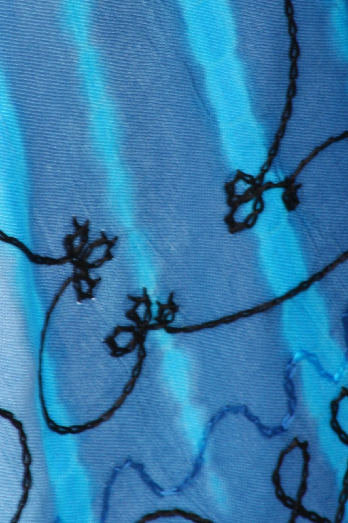 Close-up of blue fabric with black floral embroidery