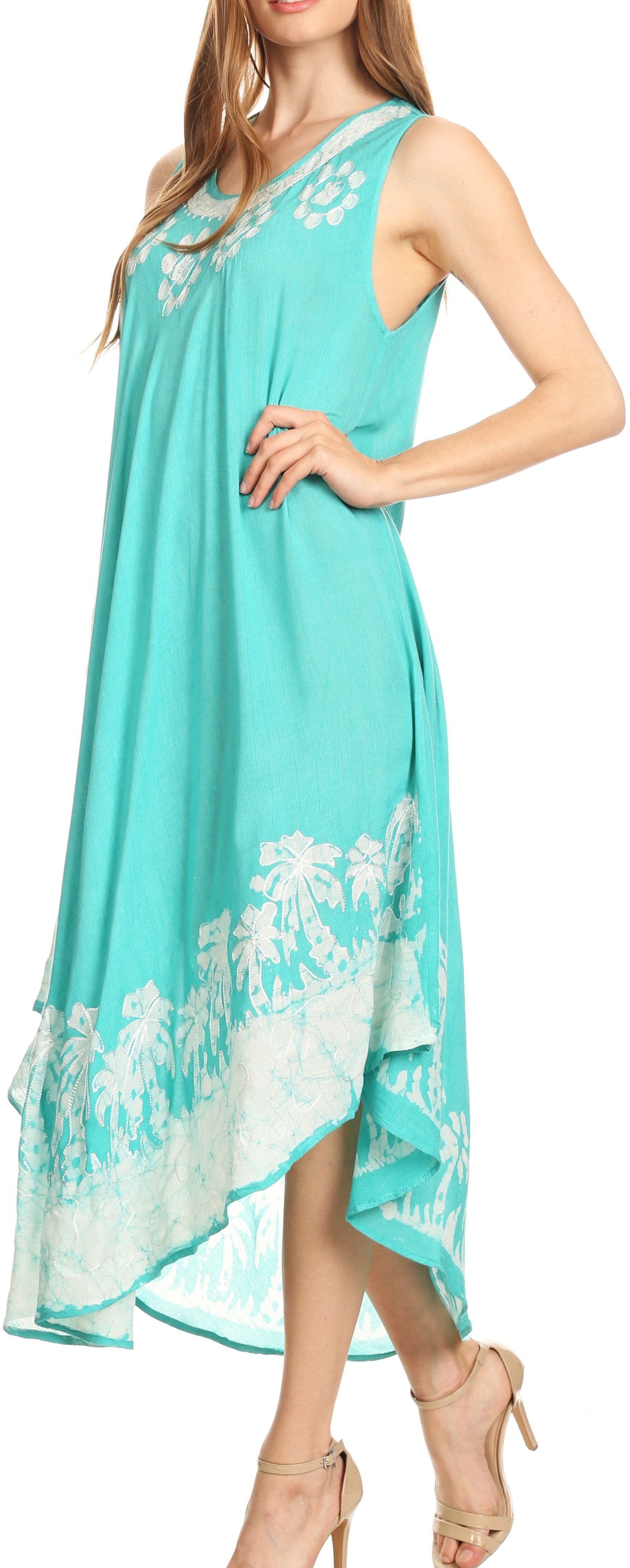 Woman wearing a turquoise dress with floral patterns, standing against a neutral background.