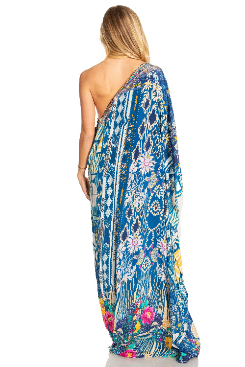 Woman wearing a colorful one-shoulder dress with a floral pattern on a white background