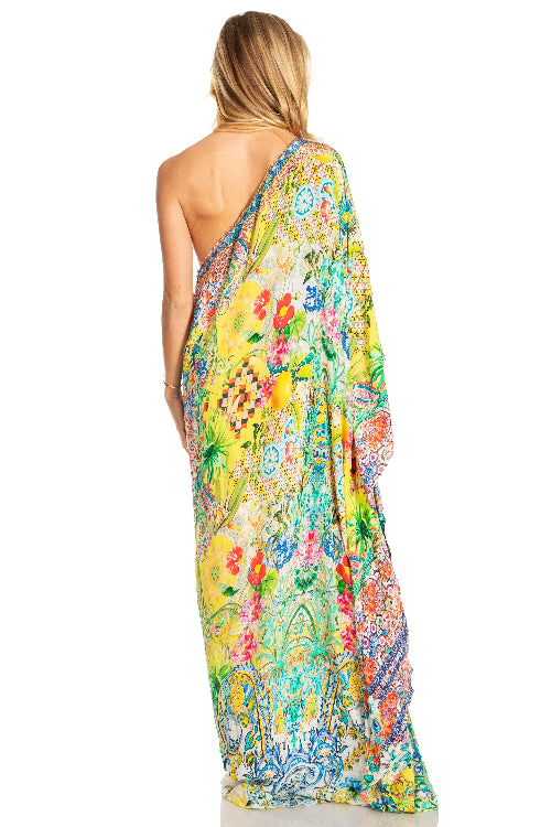 Woman wearing a colorful floral one-shoulder dress on a white background