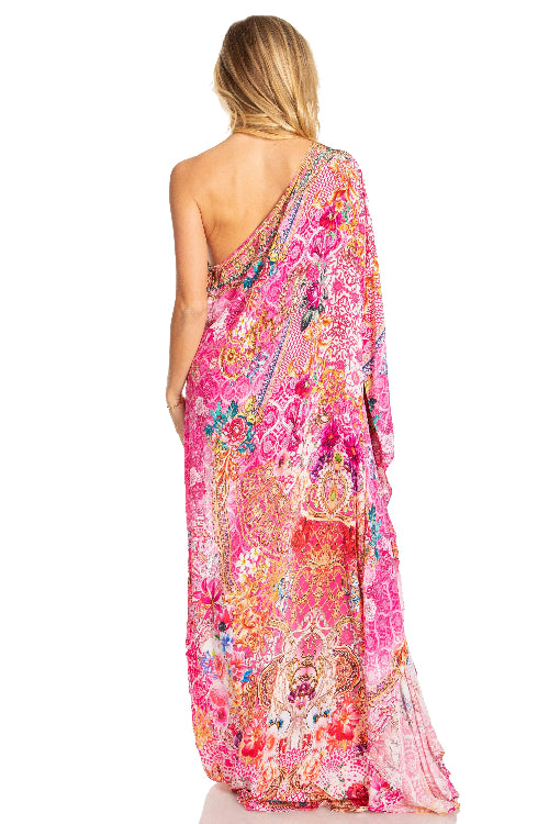 Woman wearing a vibrant pink floral one-shoulder dress on a white background