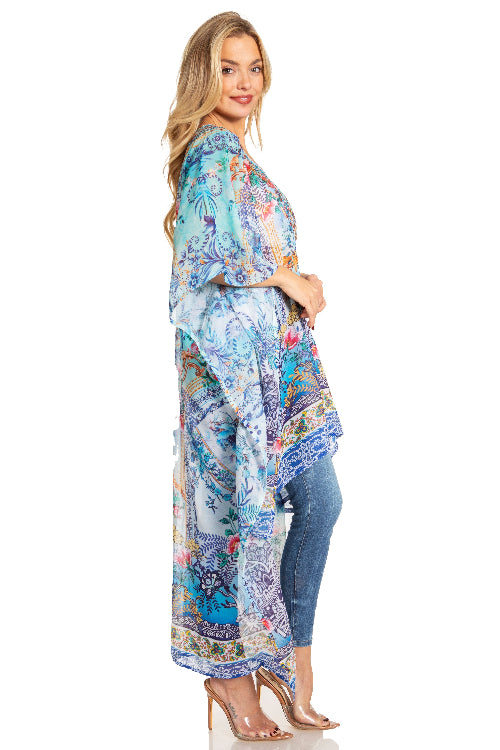 Woman wearing a colorful patterned kimono over a blue top and jeans on a white background