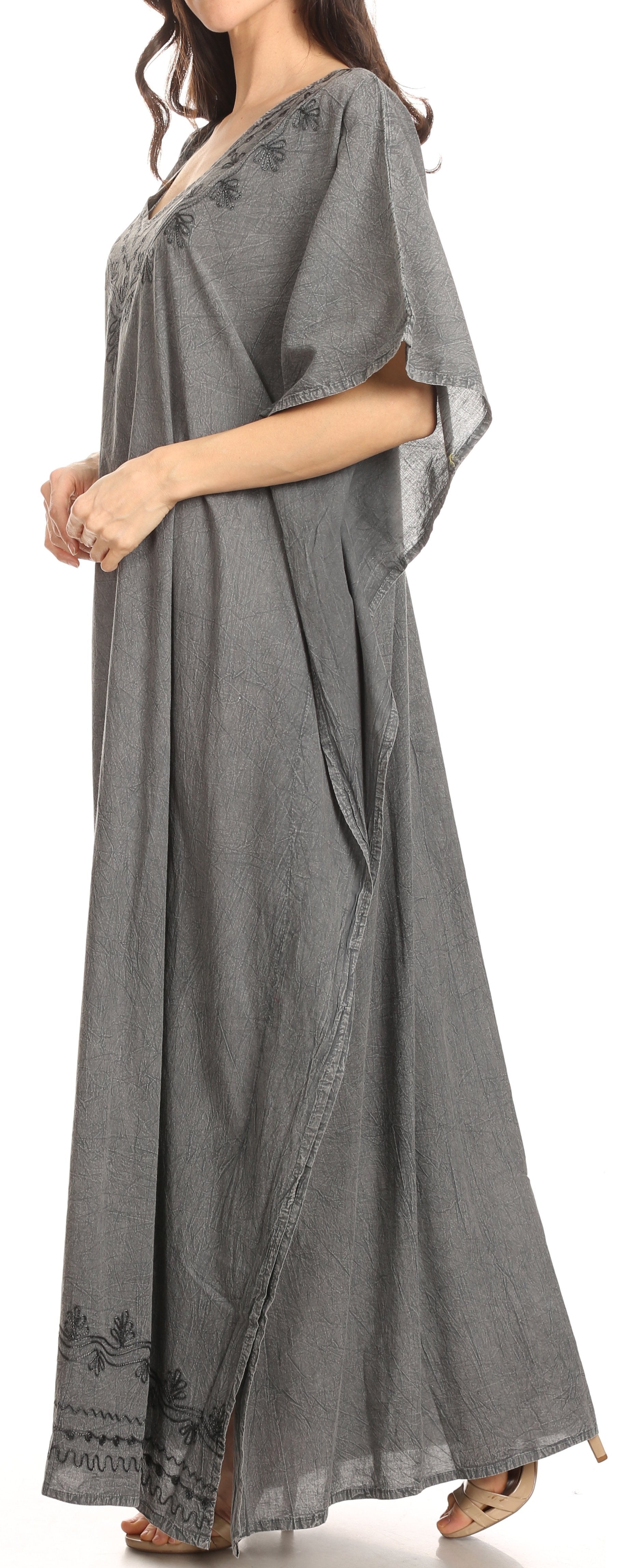 Woman wearing a long gray dress with floral embroidery on a white background