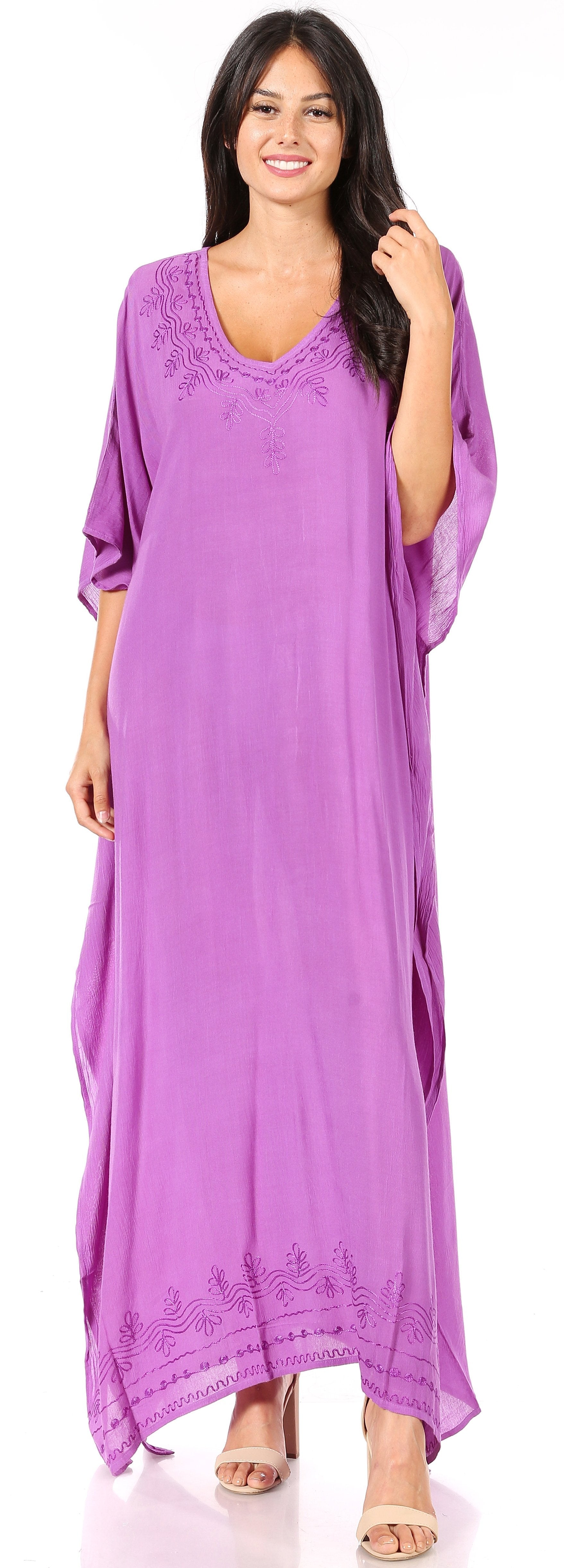 Woman wearing a long purple dress with lace details, standing against a neutral background.