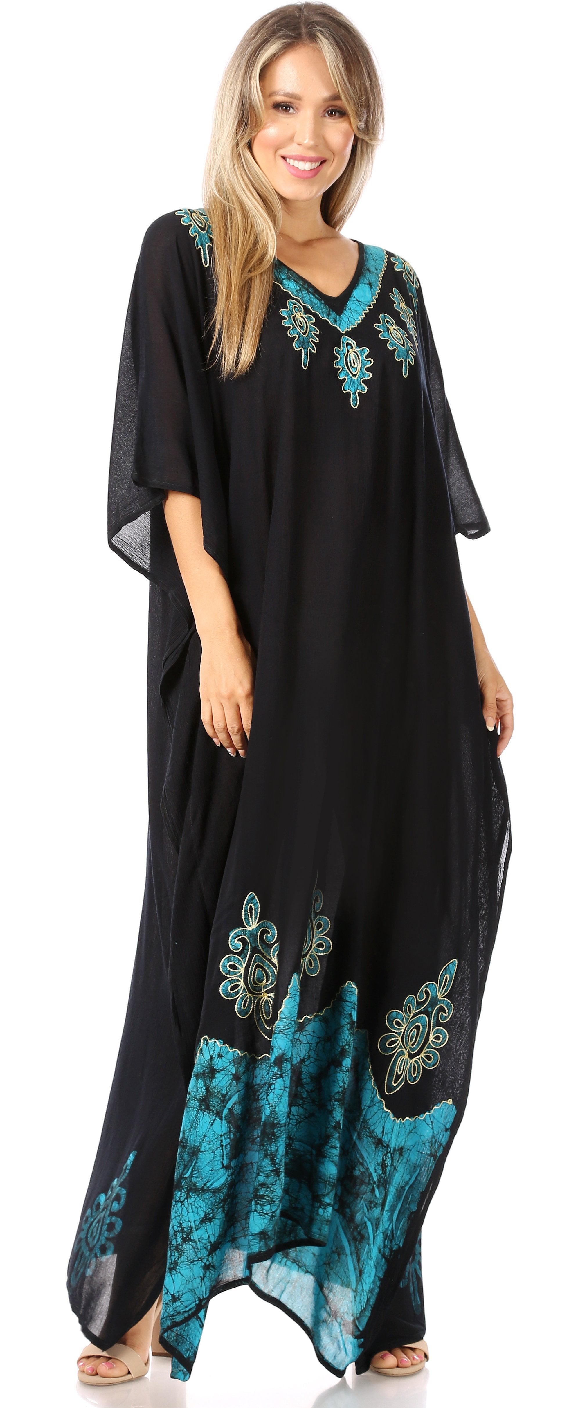Woman wearing a black caftan with teal floral embroidery on a white background