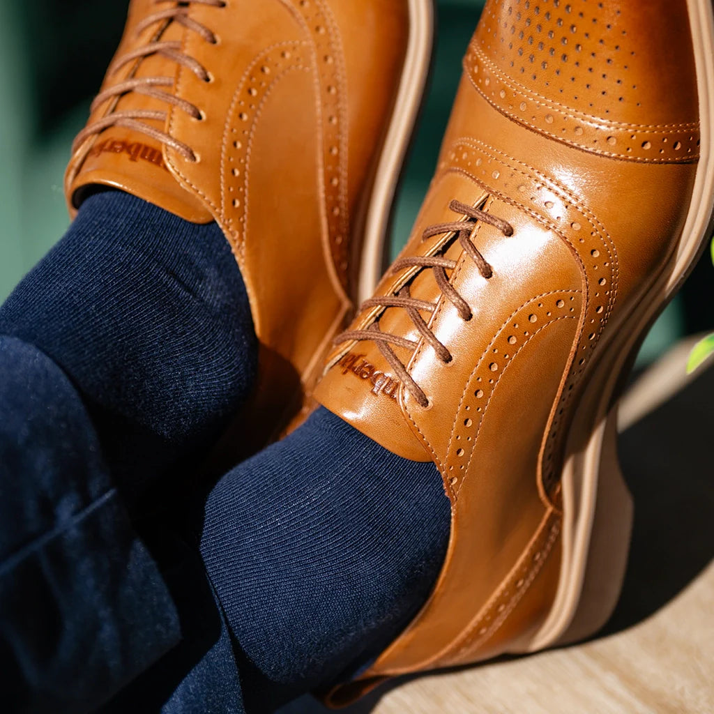 Close-up of brown leather shoes with navy socks on a blurred background