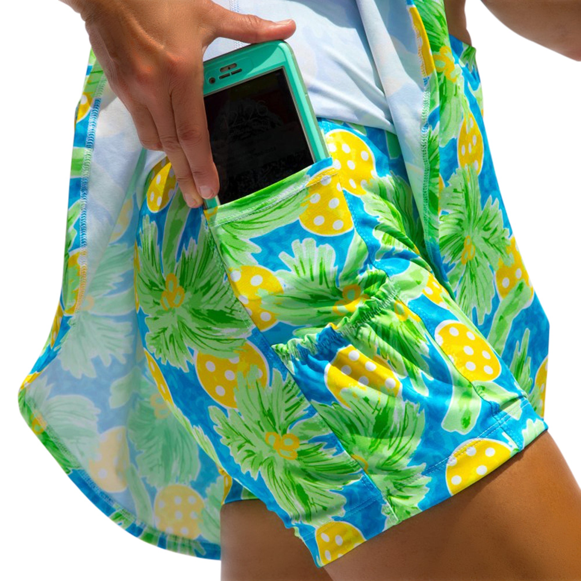 Person wearing colorful pineapple-patterned shorts with a phone in the pocket.
