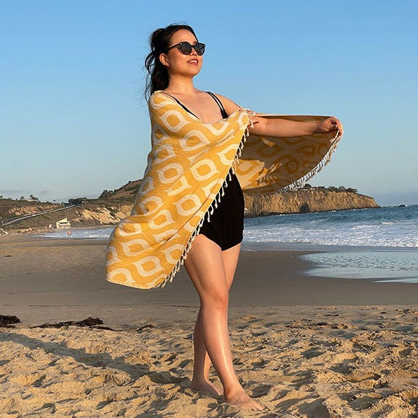 Woman on a beach holding a yellow patterned towel