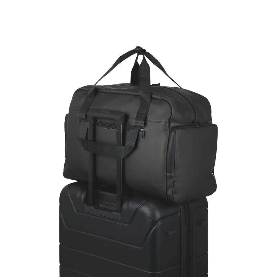 Black duffel bag on top of a black suitcase with a visible brand logo.