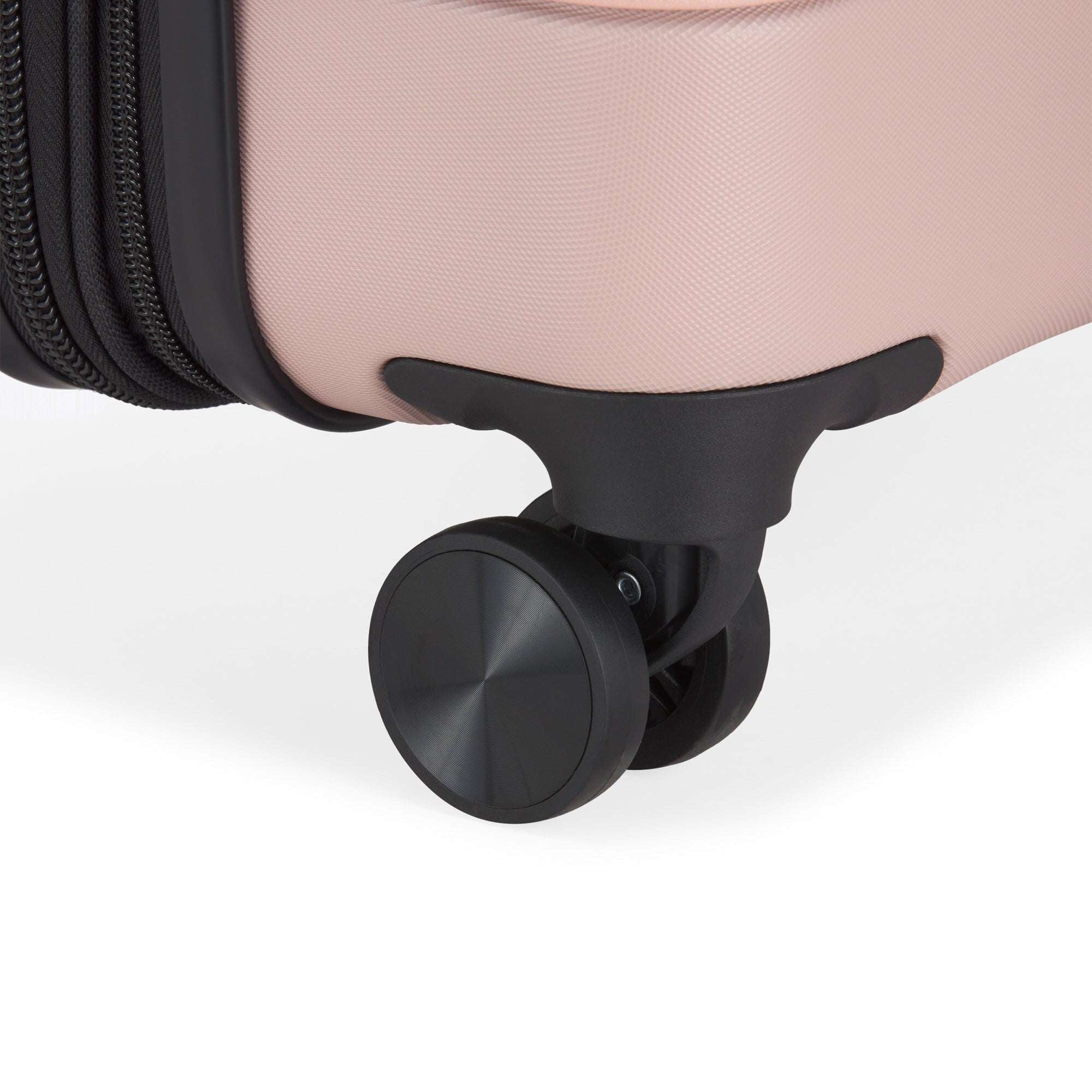 Close-up of a suitcase wheel on a light pink background
