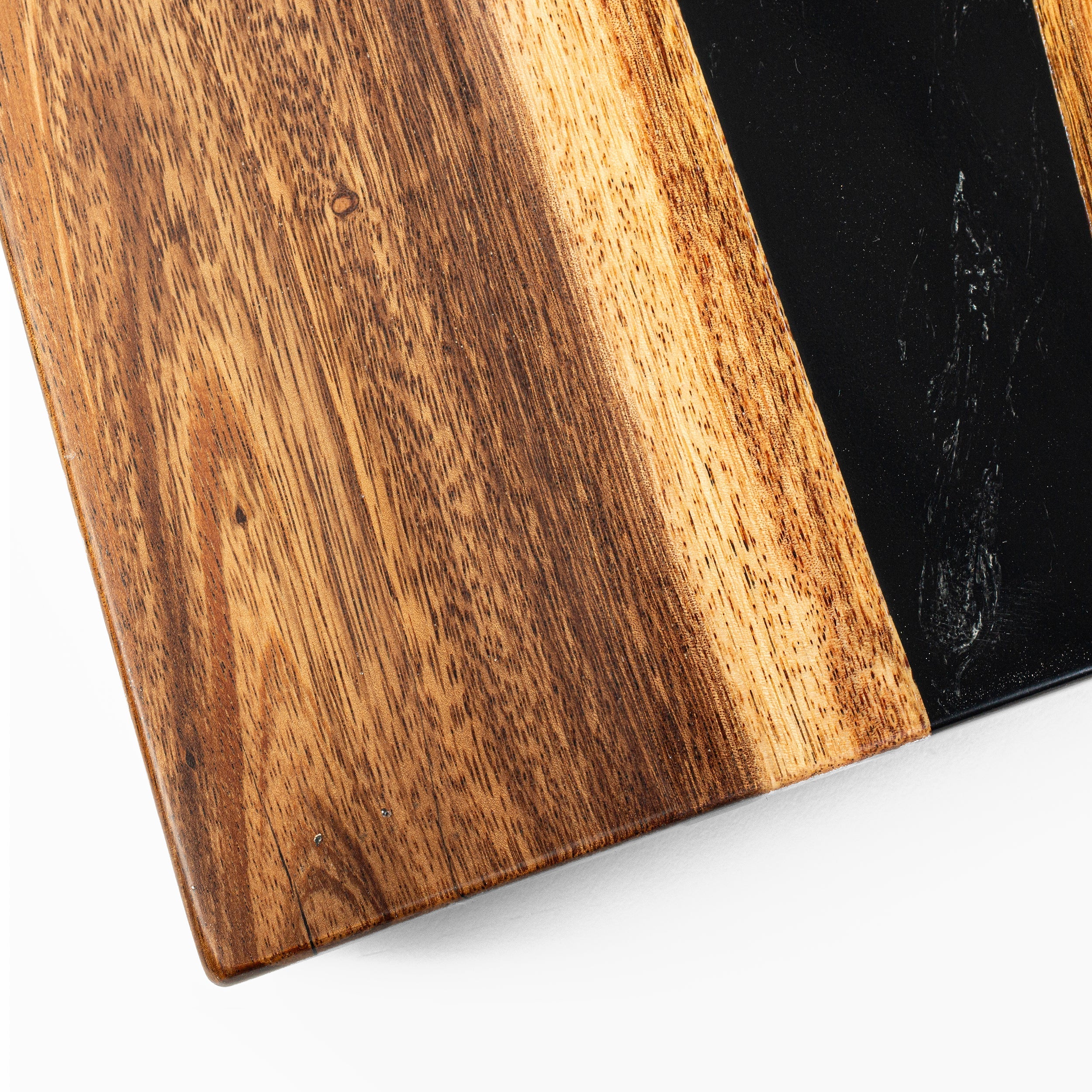 Close-up of a wooden cutting board with a black surface