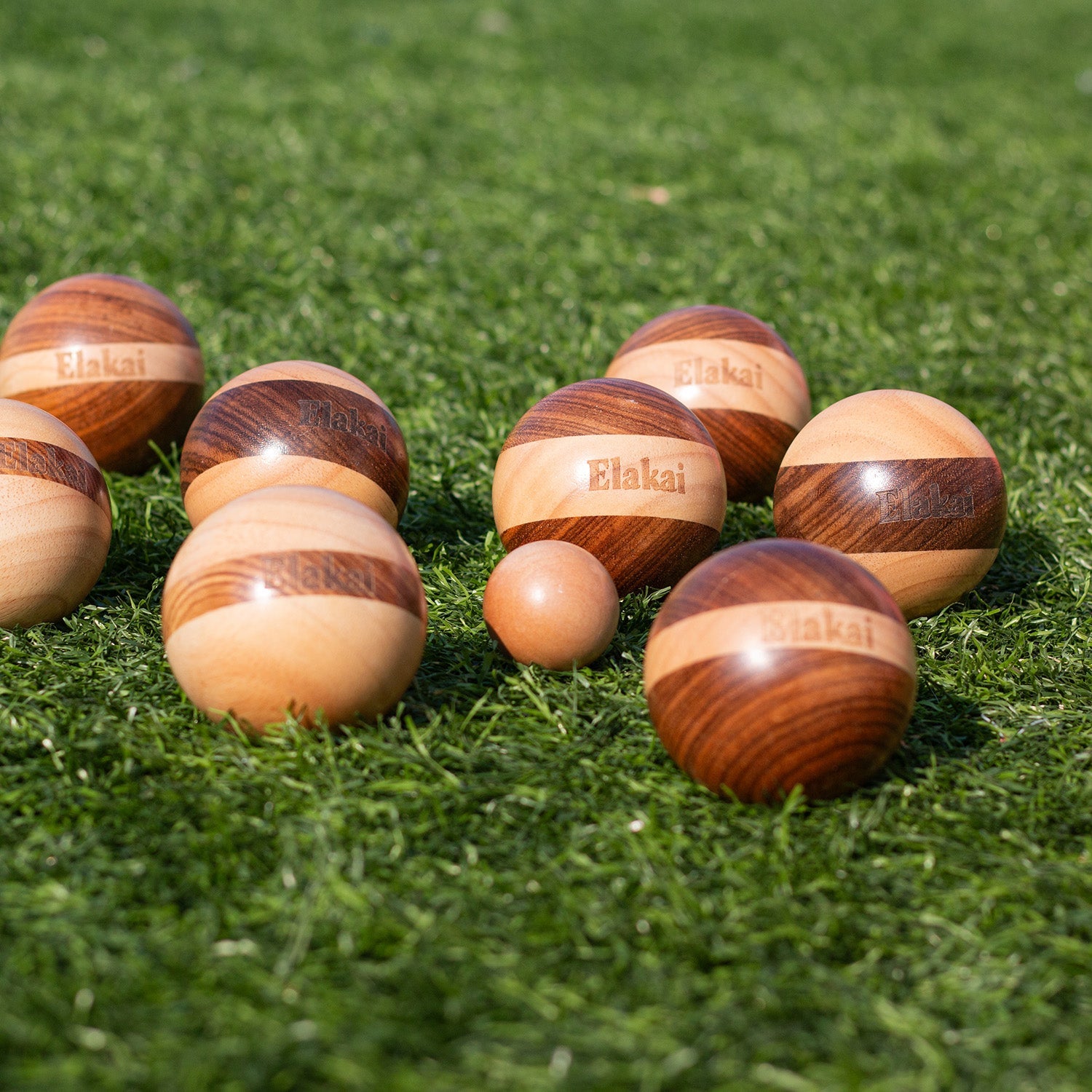Wooden balls with 'Etakai' branding on a grassy surface