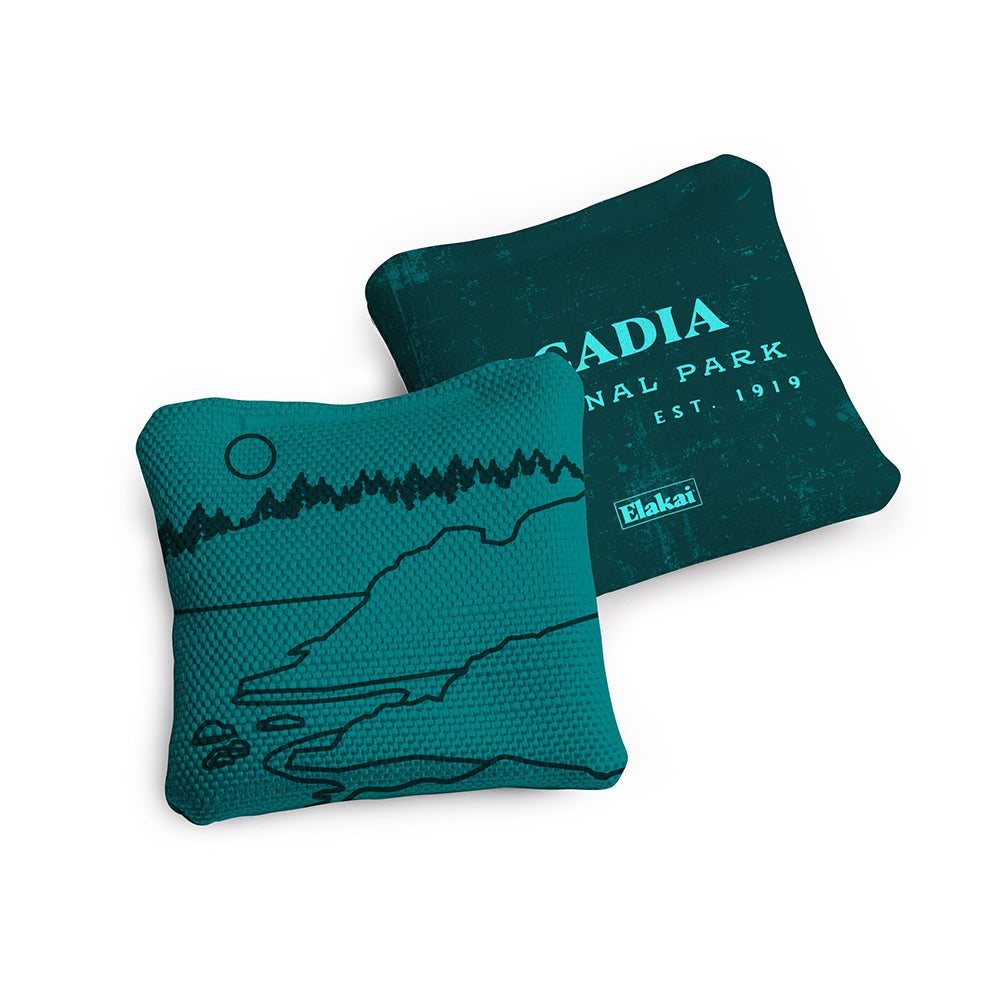 Two teal pillows with a mountain design and 'Elakai' branding on a white background