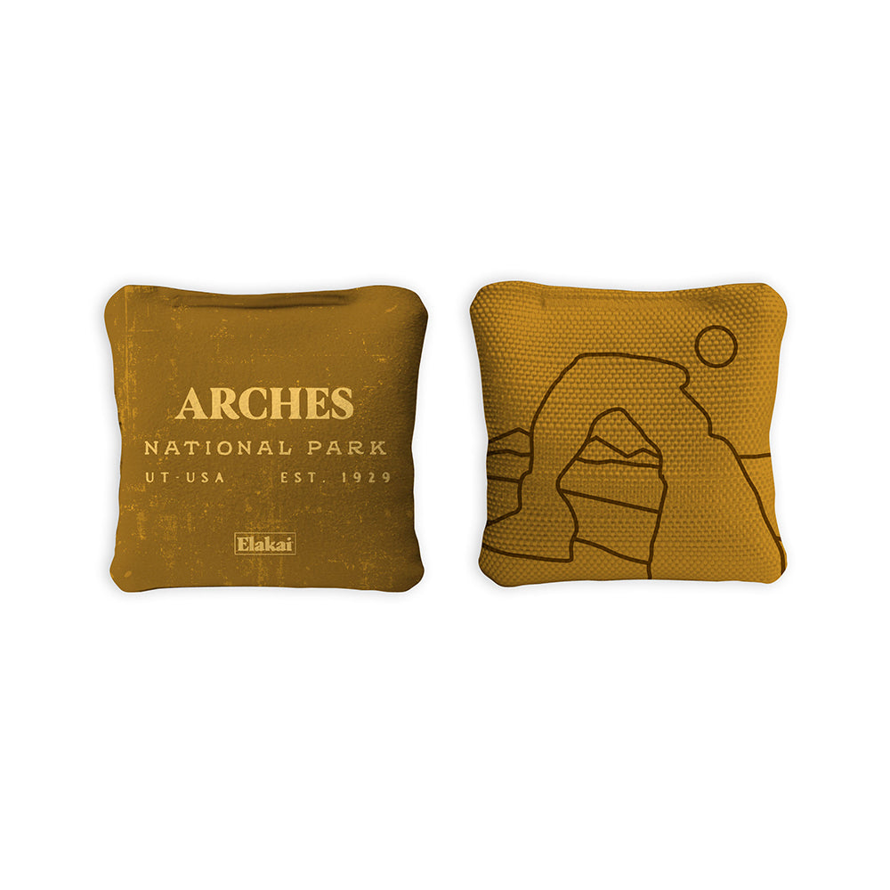 Two mustard-colored bean bags with 'Arches National Park' text and logo on a white background