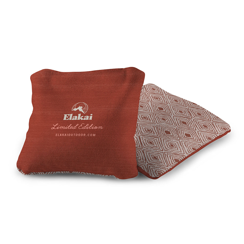Red pillow with geometric pattern and Elakai branding on a white background
