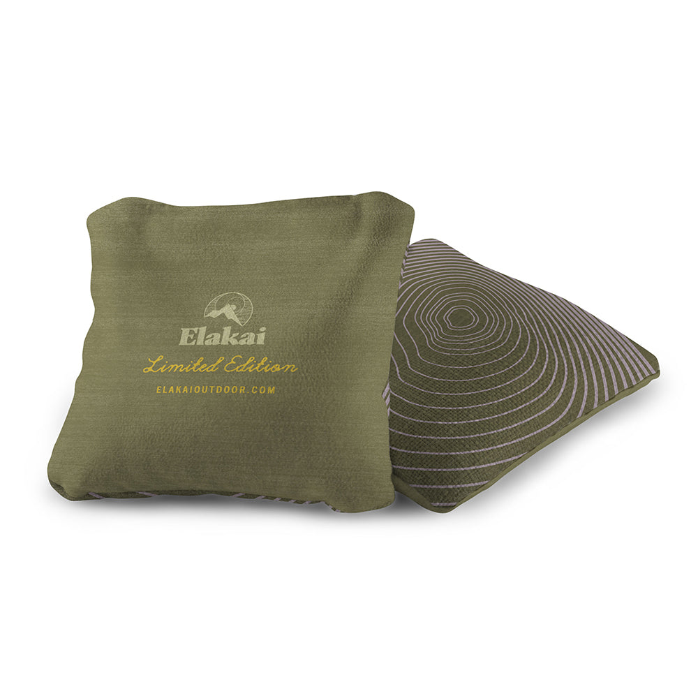 Two pillows, one green with Elakai branding and the other patterned, on a white background.