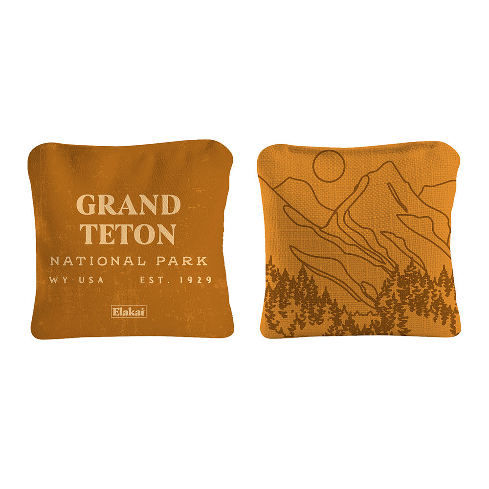 Two orange pillows with 'Grand Teton National Park' text and mountain design on a white background