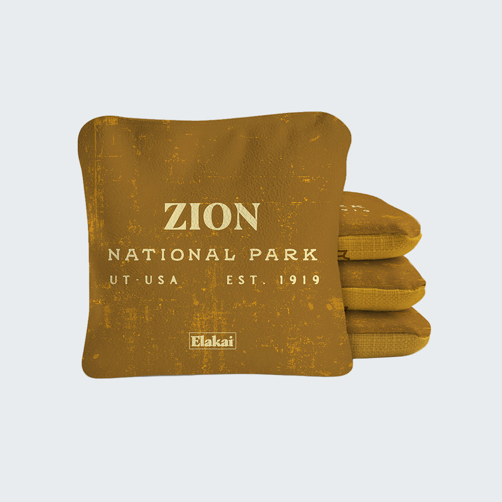 Set of mustard-colored bean bags with 'Zion National Park' text on a white background