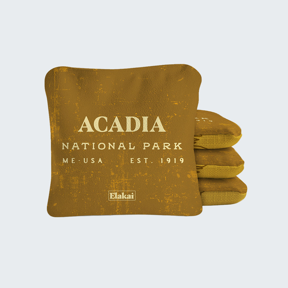 Gold-colored pillow with 'Acadia National Park' text on a white background