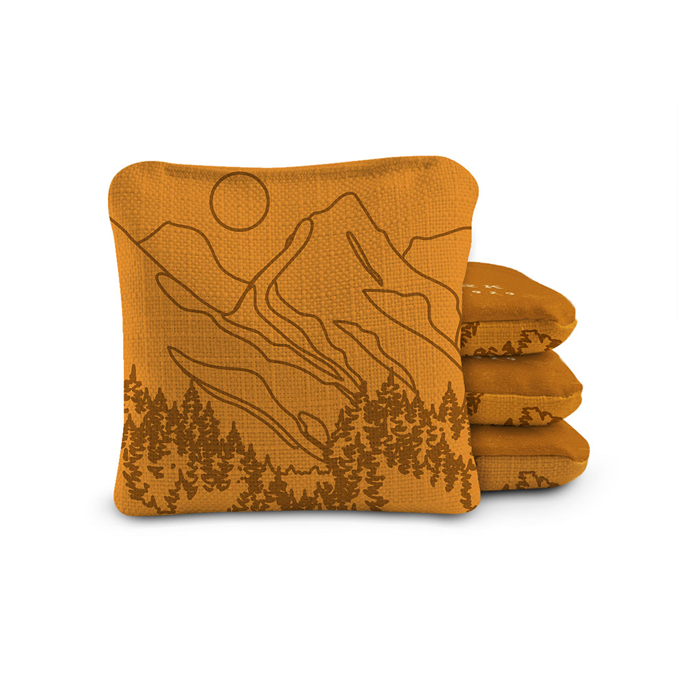 Set of four mustard yellow towels with mountain and tree design on a white background