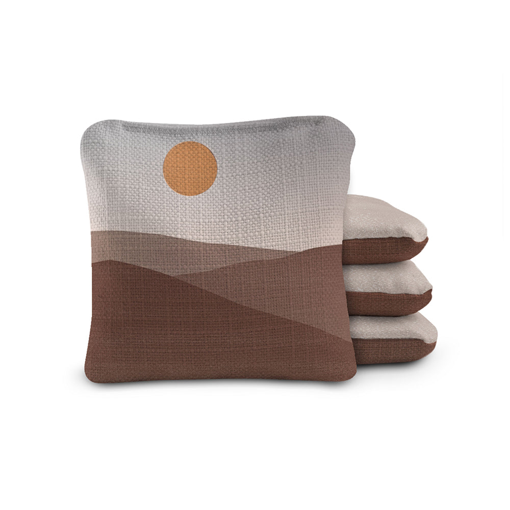 Stack of three pillows with a desert landscape design on a white background