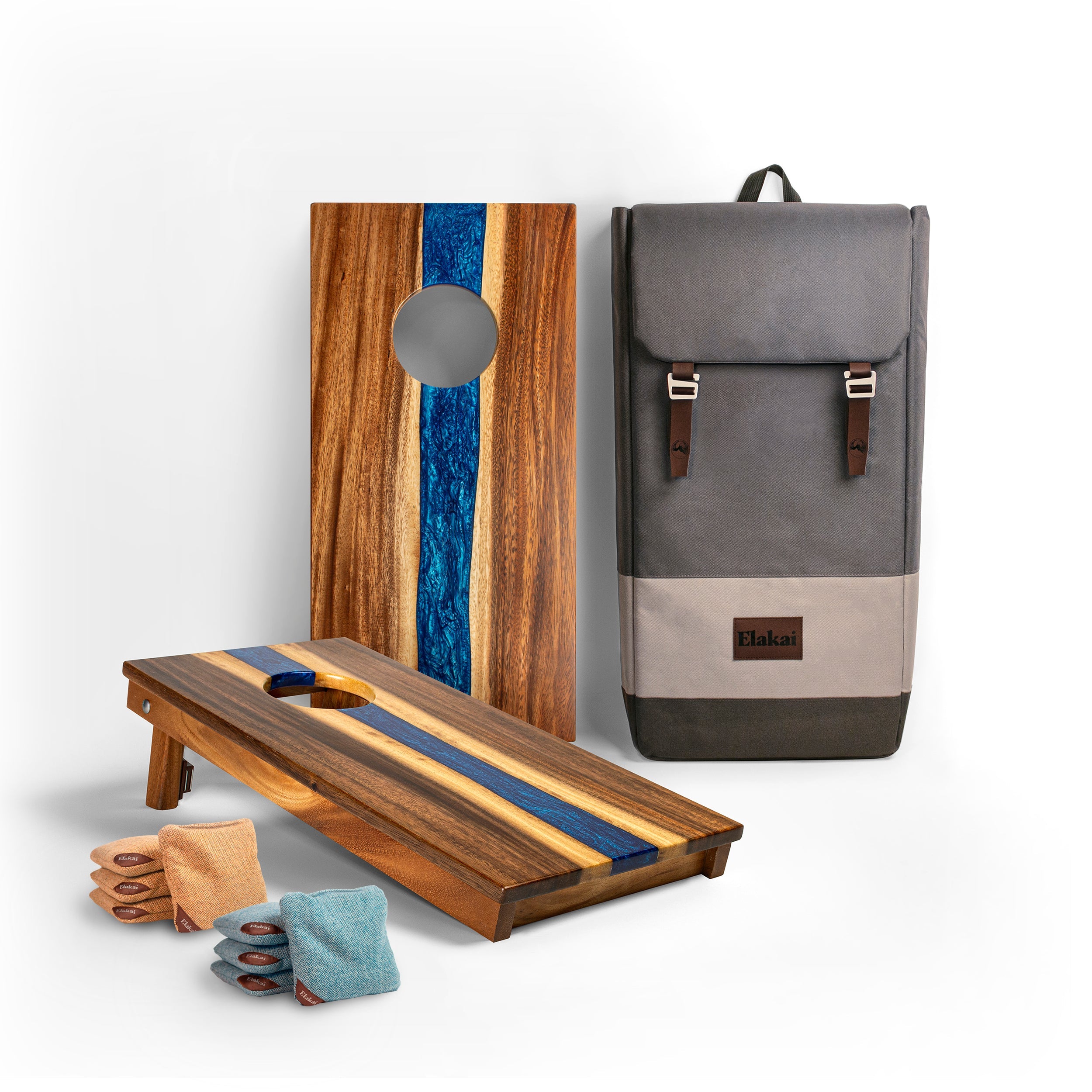 Wooden cornhole boards with blue stripes, bags, and a gray backpack on a white background