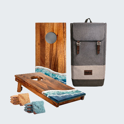 Wooden cornhole boards with ocean design, bags, and a gray backpack on a white background