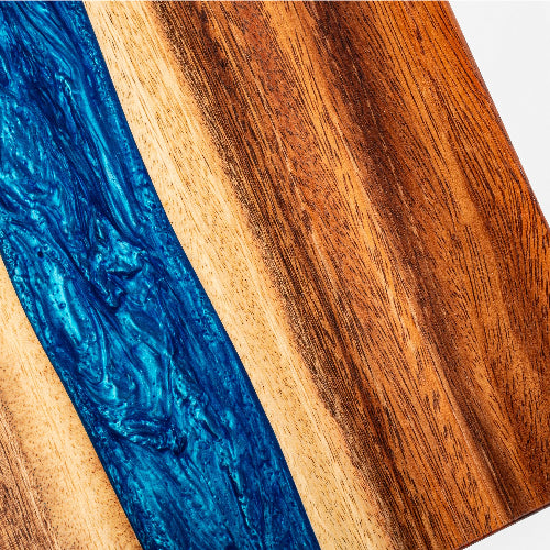 Wooden cutting board with blue resin inlay on a white background