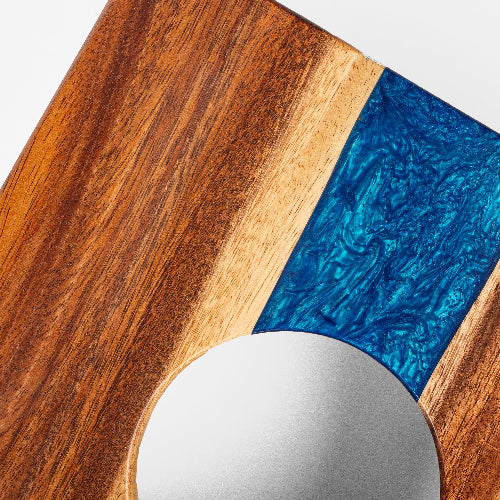 Wooden surface with a blue resin inclusion and a round mirror.