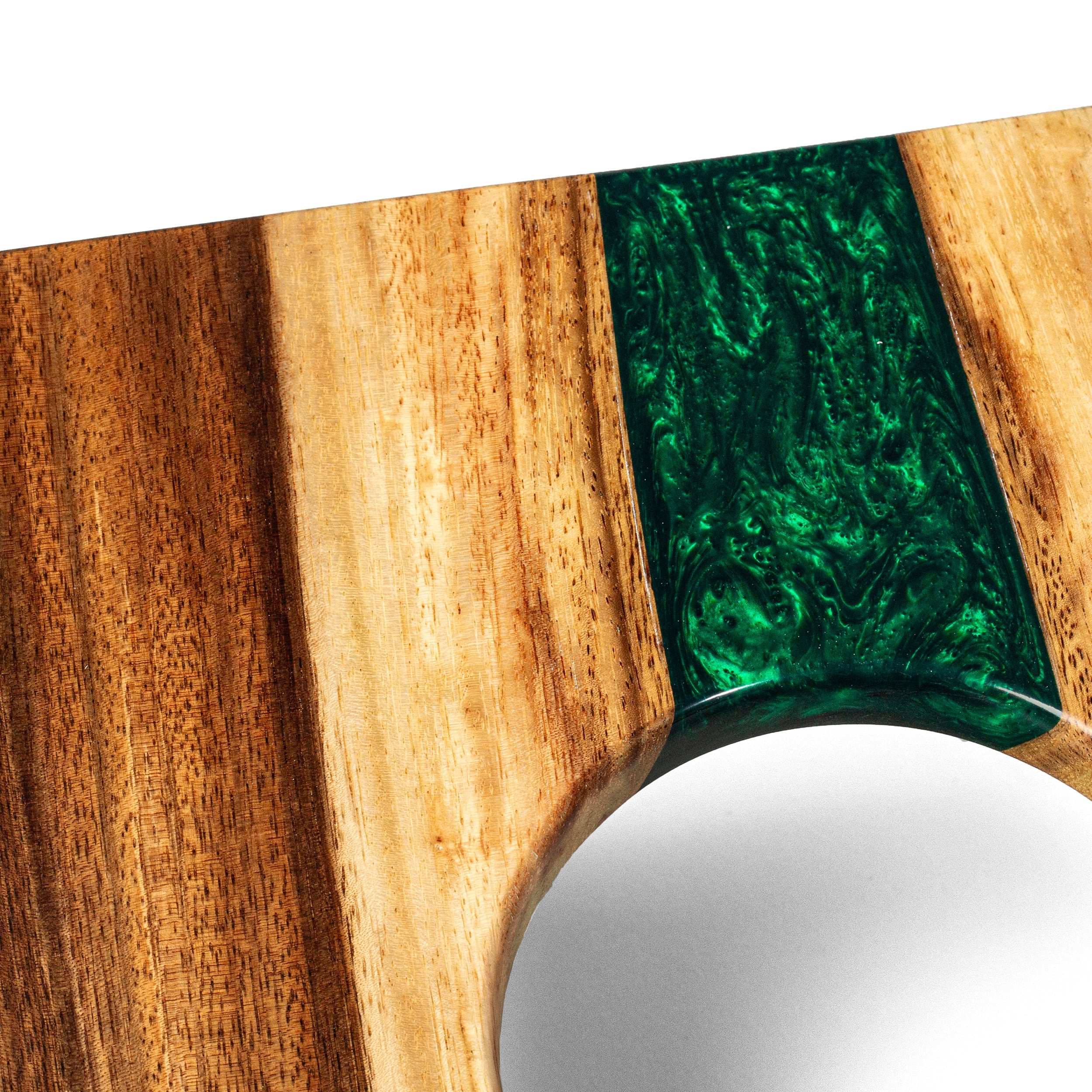 Wooden cutting board with green resin inlay on a white background