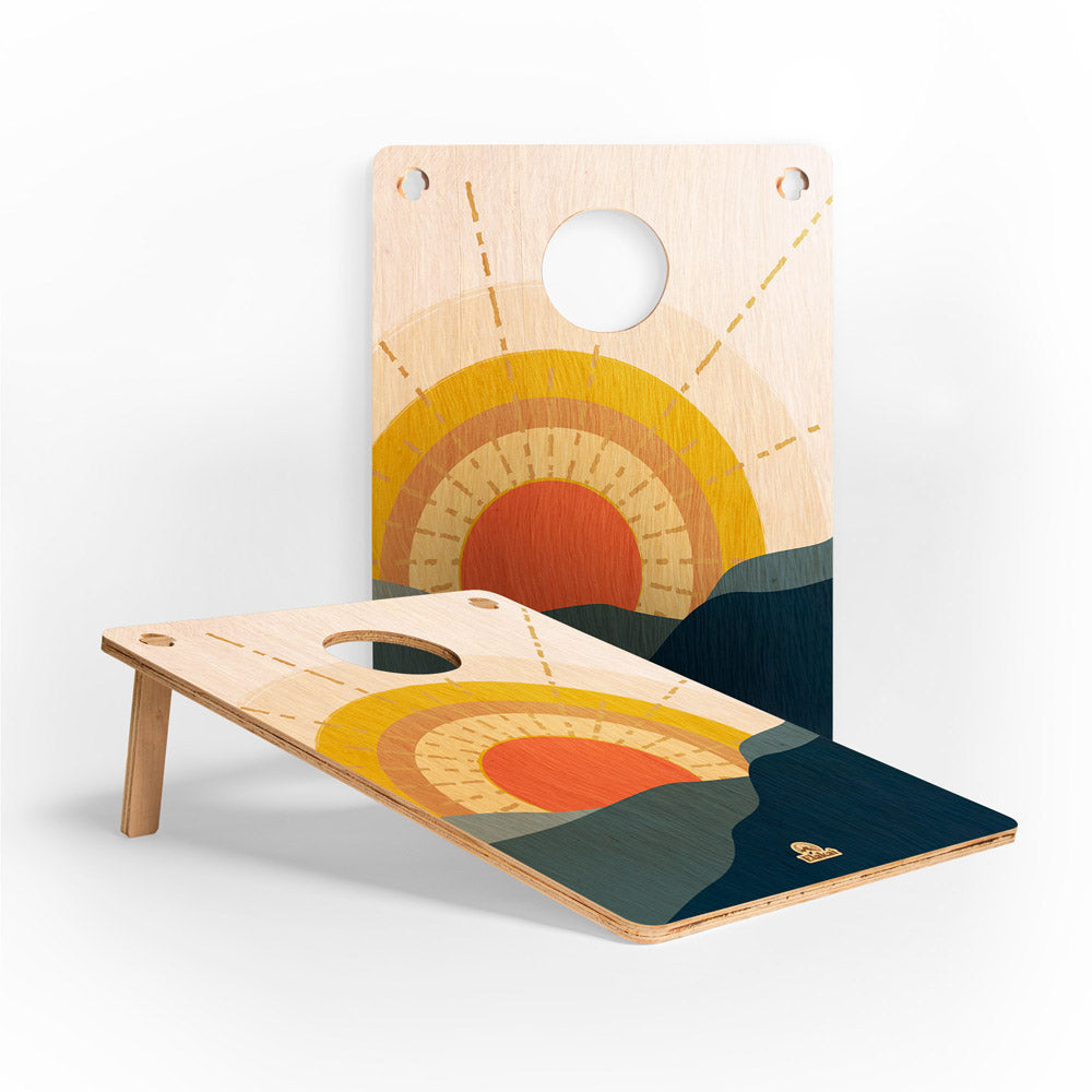 Wooden cornhole boards with sunset design on a white background