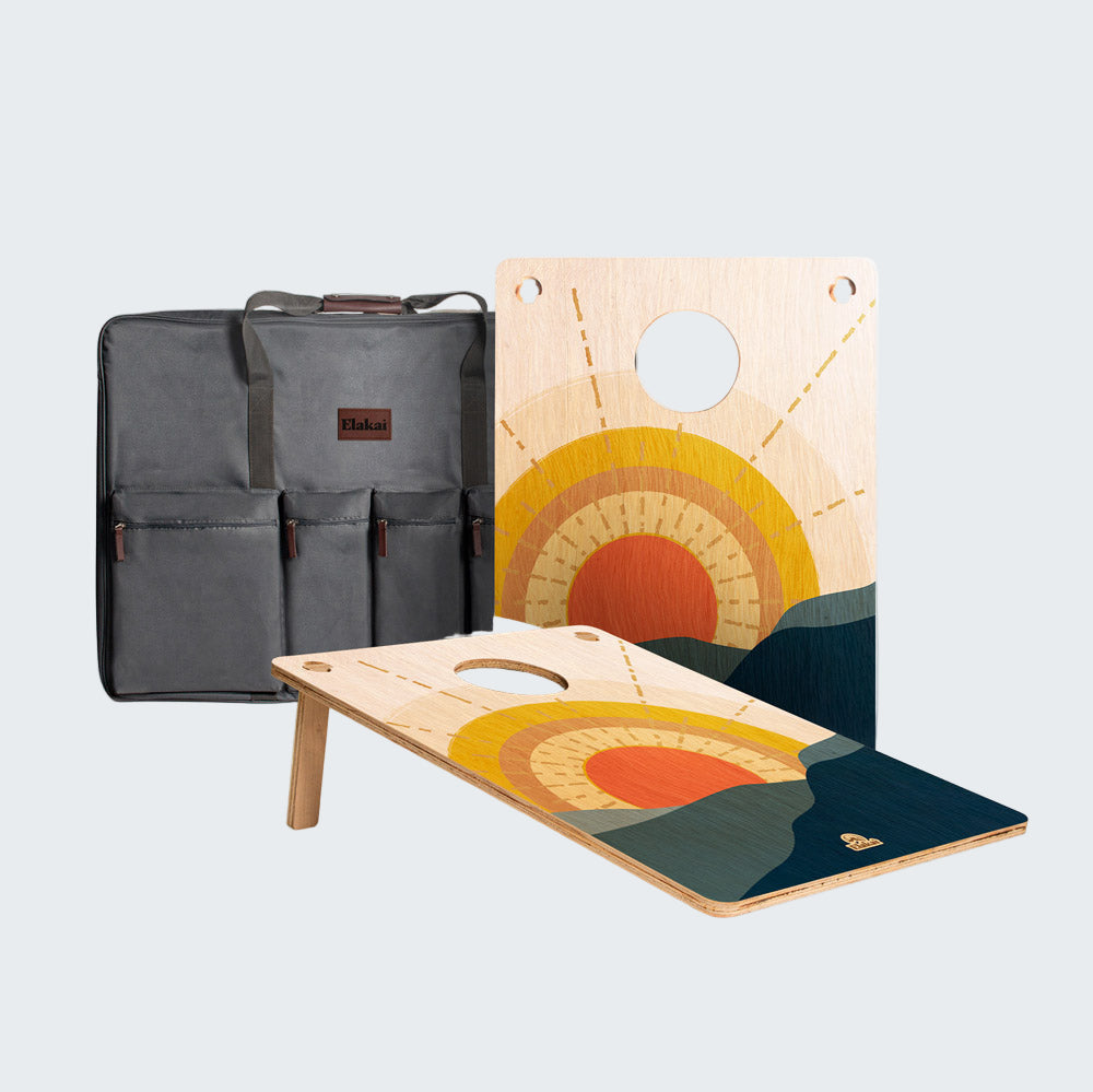 Two wooden cornhole boards with a colorful design next to a gray carrying bag on a white background