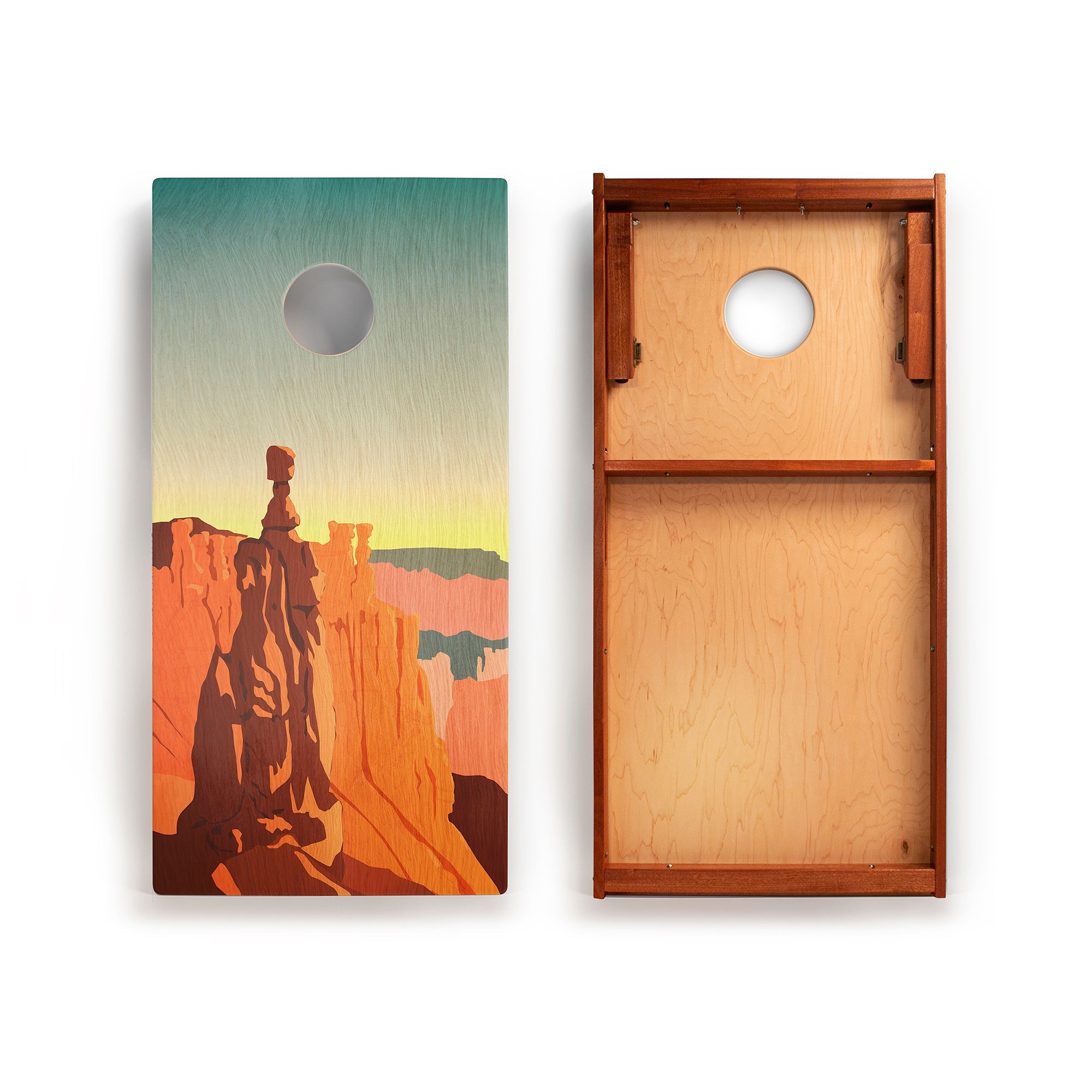 Two wooden cornhole boards with a desert landscape design on one and a plain brown board on the other.