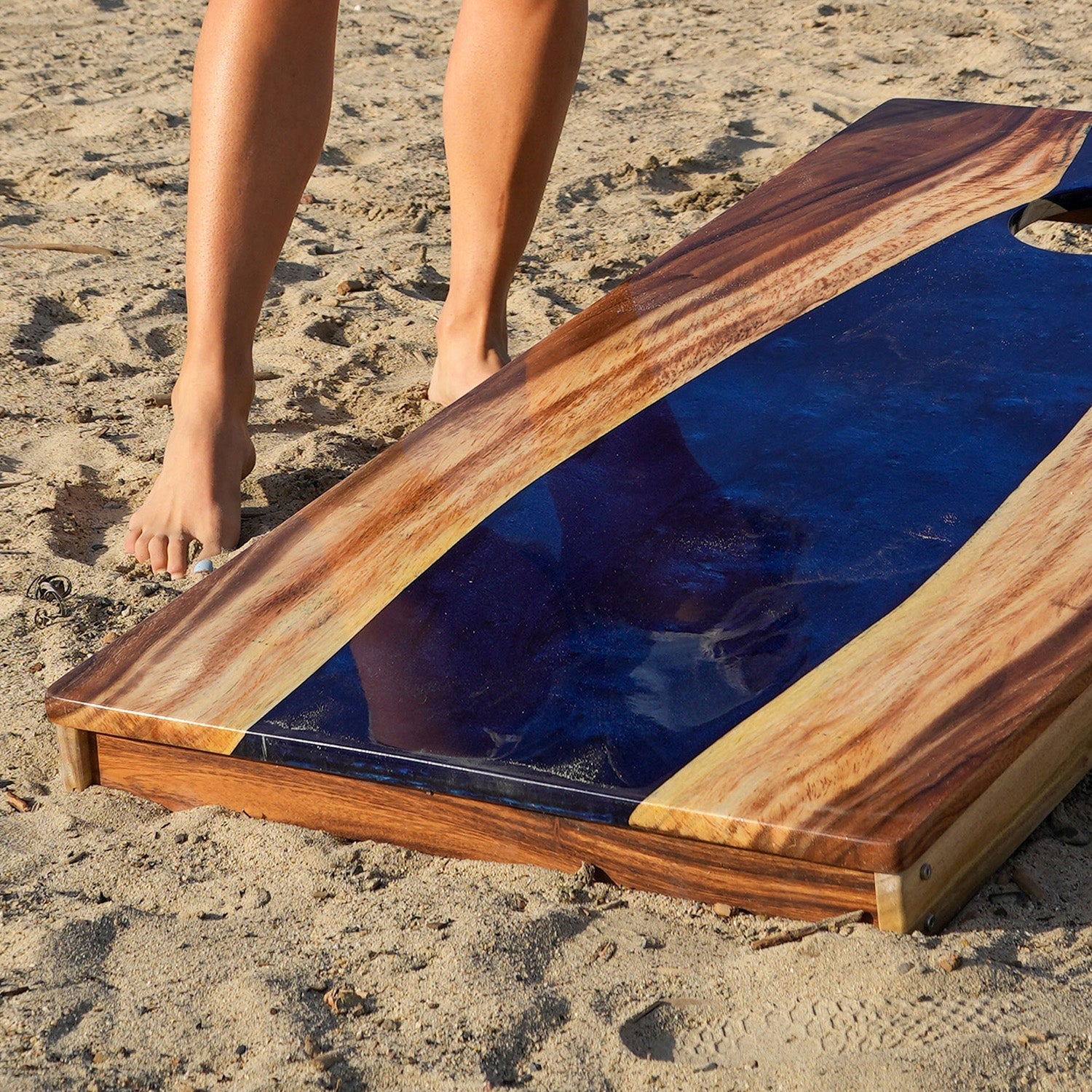 Wooden and blue resin table being set up on a sandy surface