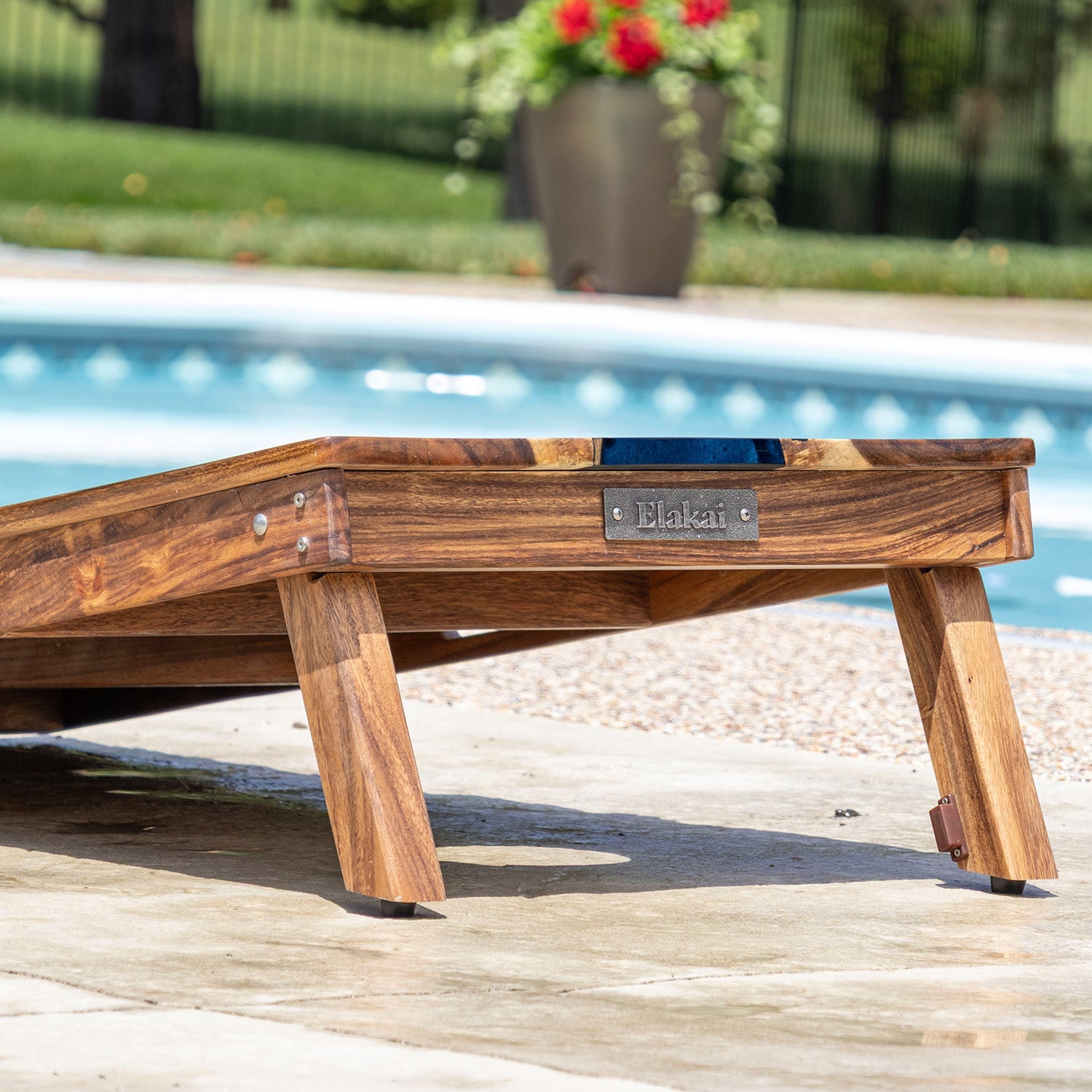Wooden lounge chair with 'Elakat' branding by a poolside