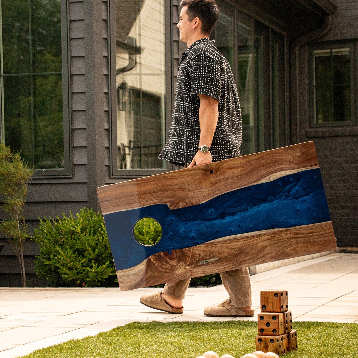 Person holding a large wooden flag with blue and brown design outdoors.