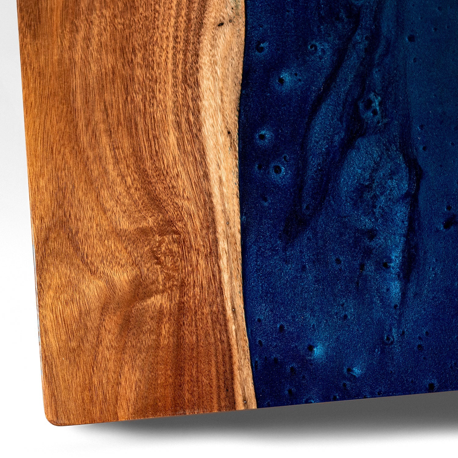 Wooden cutting board with a blue resin finish on a white background